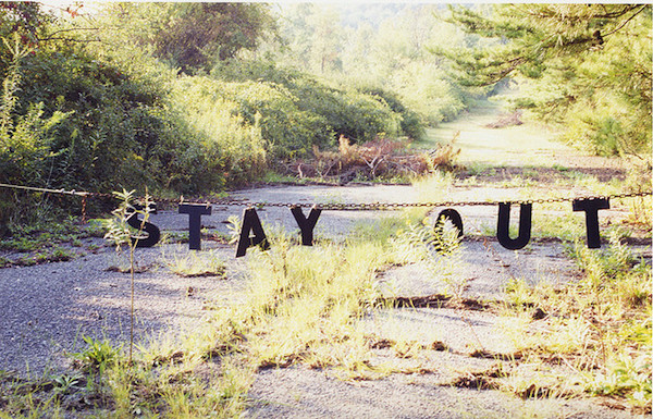Sign on a chain fence reading 'Stay Out.'