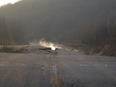 Road with cracks emitting steam and smoke.