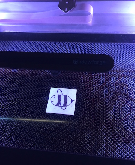 photo of a drawing of a bee on acrylic inside a glowforge laser cutter